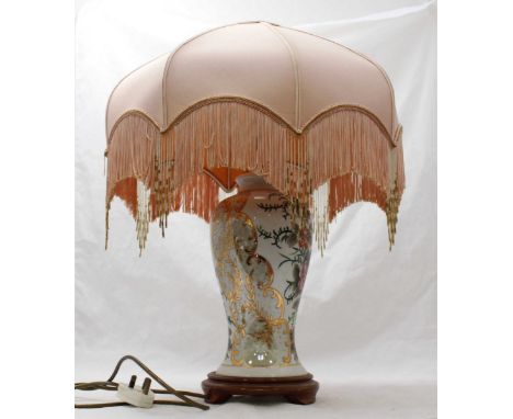 A ceramic table lamp of inverted baluster form, with gilt and floral decoration and raised on turned wooden base.