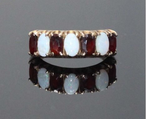 A 9ct gold opal and garnet ring, claw-set with four oval faceted garnets and three oval cabuchon opals, 2.6 grams. Size K
