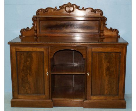 A Victorian mahogany sideboard, the raised scrolling back with shelf, above two central shelves, flanked by two panelled cupb