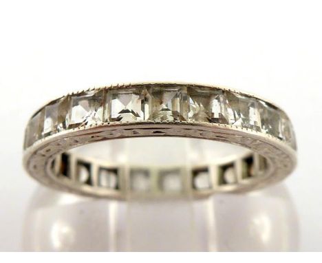 A white sapphire eternity band, composed of calibre cut stones, mounted in white metal (tests 9 carat gold), finger size K, 2