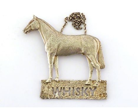 A large silver decanter label in the form of a horse, maker's mark indistinct, London, 1977, the grassy base pierced "WHISKY"