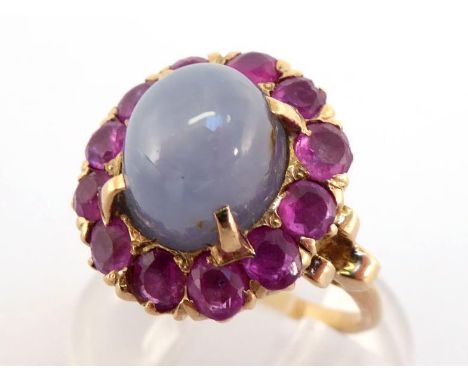 A star sapphire and ruby cluster ring, the high domed grey/blue star sapphire, in a surround of round cut rubies, mounted in 