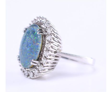 14 carat white gold high entourage ladies ring, set with a cabochon cut black triplet opal of approximately 1.4 x 1.1 cm. and