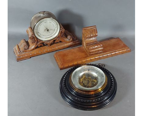 A Negretti and Zambra brass cased barometer thermometer with carved oak stand and wall bracket together with an ebonised case