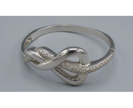 An 18ct white gold diamond set bangle of shaped scroll form, set with lines of diamonds, 71.7 grams, 7cms X 6cms 