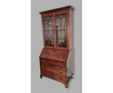 A George III mahogany bureau bookcase, the moulded cornice above two arched glazed doors enclosing shelves, the lower section