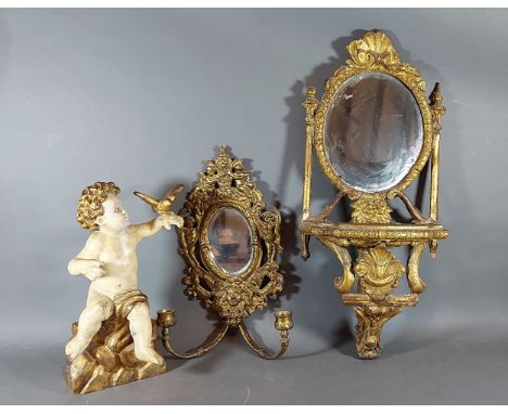 A gilded wall bracket with oval mirrored back together with a brass girandole and a carved gilded figure 