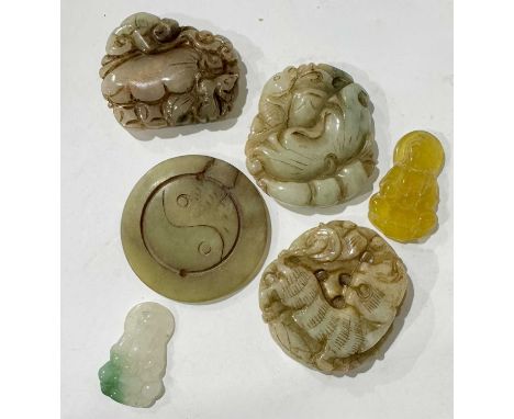 A collection of Chinese jade-type and Nephrite pendants carved with tiger, fish, floral and yin-yang symbols together with ye