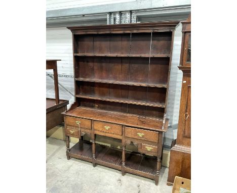 A George III oak dresser and rack, circa 1760, the three bay base of short drawers with swan neck brass handles, supported on