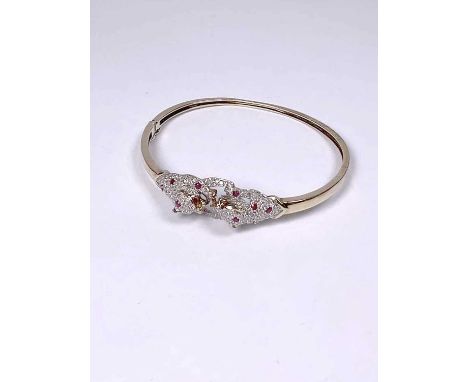 A diamond and ruby panther bangle bracelet, estimated total diamond weight 0.60ct, stamped 9k, inner diameter 6.2cm, 12g