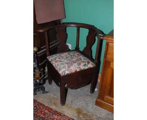 A Georgian Oak corner Commode Chair having curved backrest on turned supports and fretworked splats, standing on square legs,