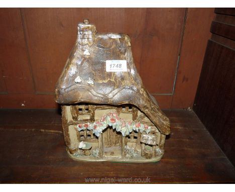 A pottery table lamp base in the shape of a thatched cottage.