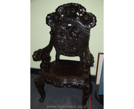 An imposing ebonised open armed chinoiserie Armchair, the panel to the back decorated with birds amidst exotic flower blooms,