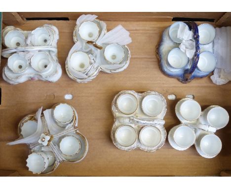 Six ceramic egg cruets, all with four egg cups, tallest 12cm