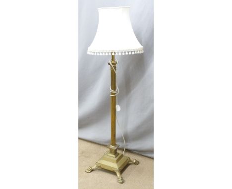 A brass standard lamp with stepped base raised on four lion pad feet, H140cm
