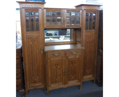 Arts and Crafts oak breakfront dresser, having central double cupboard with bevelled glazed doors, mirror below and two drawe