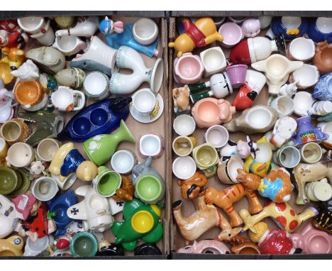 Two trays of novelty ceramic egg cups including aeroplane, figural and animal related items