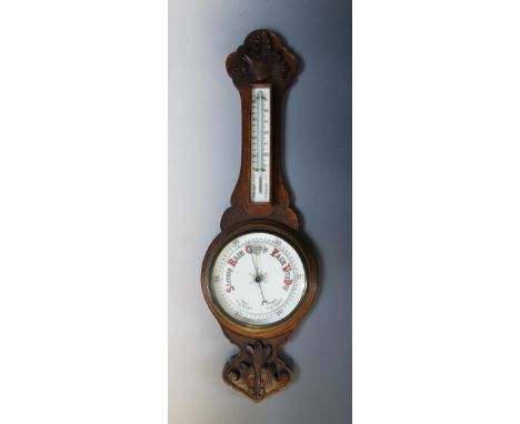 A Victorian carved oak aneroid wall barometer, with a 20cm white enamel dial and a conforming white thermometer back plate, 8