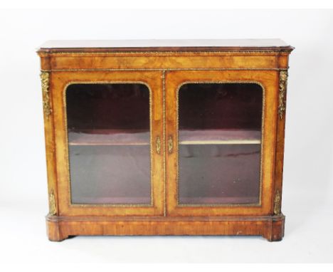 A Victorian burr walnut pier cabinet, the shaped and cross banded, ogee moulded top above twin glazed doors enclosing a velou