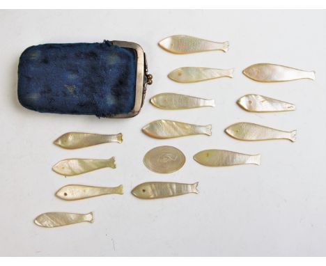 An assorted collection of mother of pearl carved counters in the form of fish and further oval examples, with a silver napkin