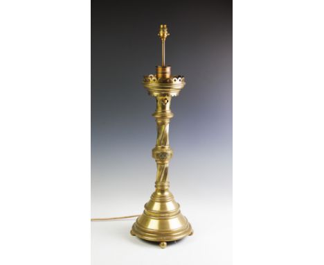An ecclesiastical brass lamp base of large proportions, the lamp holder raised above a scalloped gallery with pierced quatrof