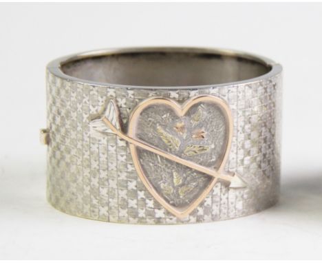 A Victorian sentimental bangle, the half hinged bangle designed as a gilt relief heart design with piercing arrow, enclosing 