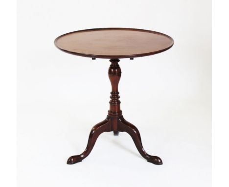 A George III style mahogany tripod table, the circular tray top on ring tuned baluster shaft, three down-swept supports and p