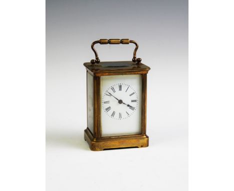 An early 20th century brass cased carriage timepiece, with swing handle above a white enamel, Roman numeral dial, brass key, 