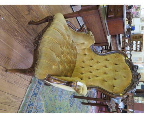 A Victorian style carved wood button back armchair, with foliate scroll decoration