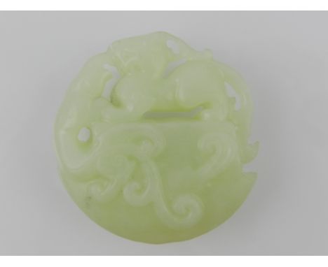A Chinese jade pendant, depicting a dragon upon stylised waves. Diameter. 6cm