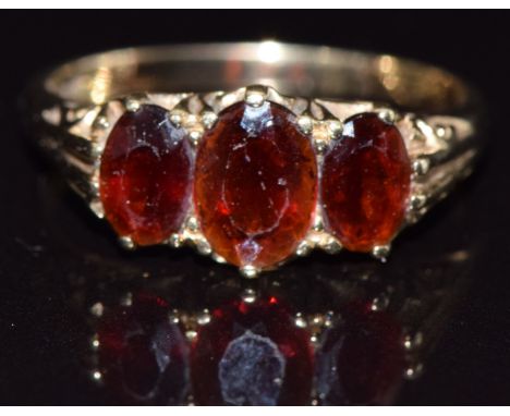 A 9ct gold ring set with three oval garnets, size O, 2.7g