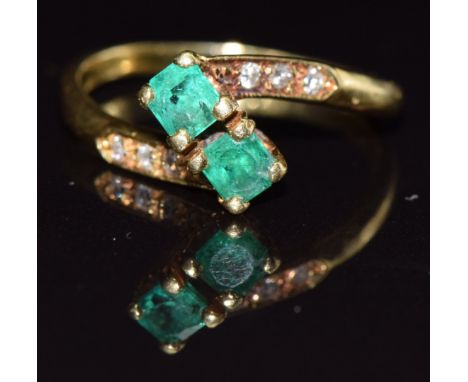 An 18ct gold ring set with two emeralds and diamonds, size M, 3.4g