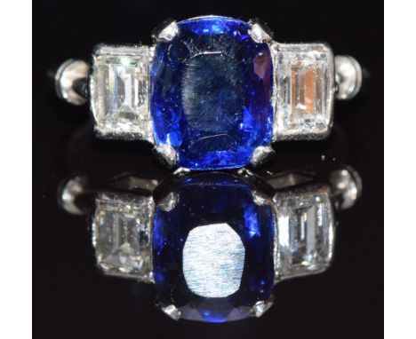 A platinum ring set with a cushion cut sapphire of approximately 3.1cts, flanked by a diamond of approximately 0.5ct&nbsp;to 