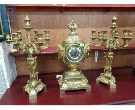 STUNNING GILT BRONZE CLOCK SET WITH FRENCH MOVEMENT ADORNED BY LION HEAD HANDLES TO EACH SIDE &amp; WITH A PAIR OF 7 BRANCH C