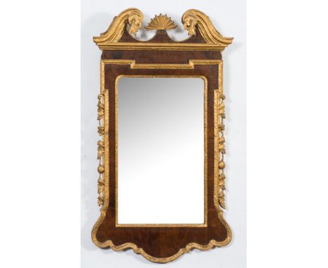 An early 18th Century walnut and carved gilt wood wall mirror:, the moulded swan neck pediment with foliate ornament centred 