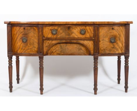 An early 19th Century mahogany bow-fronted sideboard:, fitted with a central frieze and recessed arched apron drawer, flanked