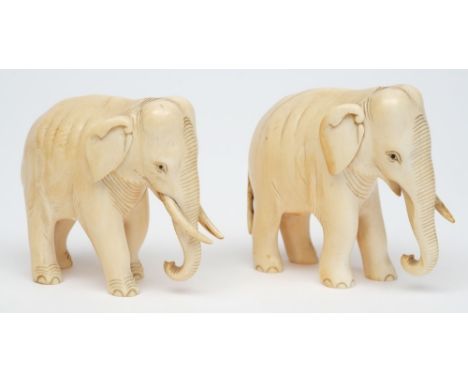 A pair of early 20th century carved ivory Indian elephants: with curved trunks and inset ebony eyes, 8cm. high, (one trunk mi