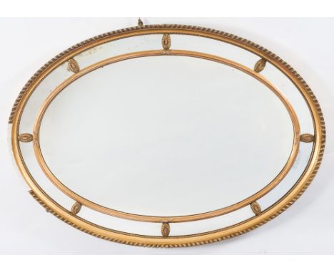 A giltwood and gesso oval marginal wall mirror:, the plate within a reeded and ribbon cross frame, applied with paterae and w