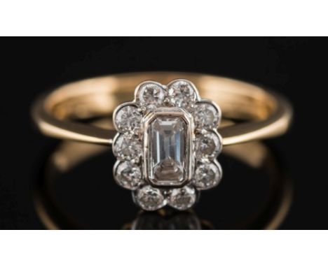 An 18ct gold and diamond oval cluster ring:, the central, baguette-cut diamond estimated to weigh 0.20ct, within a surround o