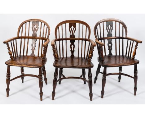 A harlequin set of four early 19th Century elm, ash and fruitwood stick back Windsor elbow chairs:, the backs each with a pie