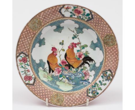A Chinese ruby-backed famille rose dish: finely painted with a pair of cockerels in a garden setting with pierced rockwork an