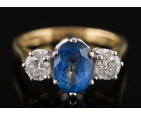 An 18ct gold, sapphire and diamond three-stone ring:, the oval  sapphire approximately 8mm long x 6mm wide, between circular,