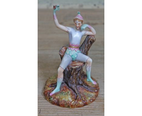 A rare and unusual Royal Worcester porcelain figure depicting a jester or pixie holding a flower and sat on a tree trunk, gre