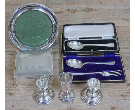 A mixed lot of hallmarked silver comprising a cigarette box, a photo frame, a pair of candlesticks, a posy, a cased christeni