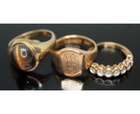 A group of three hallmarked 9ct gold rings comprising one set with a tiger's eye cabochon, a signet ring and another set with