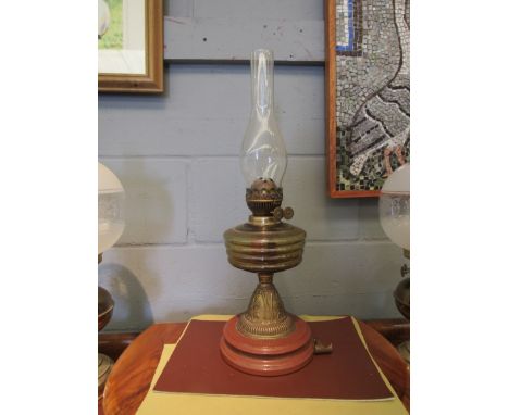 A Victorian oil lamp with ribbed glass reservoir and embossed brass column 
