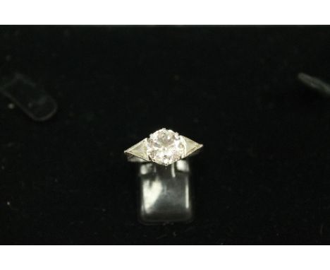 A diamond ring, the central diamond approximately 3ct, surmounted on each side by a triangular-cut diamond each approximately