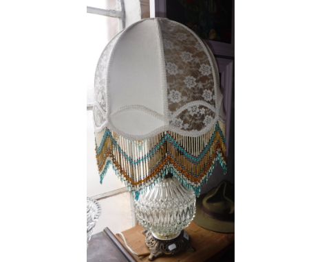 A GLASS BODIED TABLE LAMP with brass fittings, the shade with beaded decoration