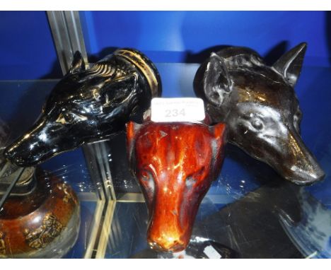 THREE BLACK GLAZED CERAMIC STIRRUP CUPS in the form of fox's heads