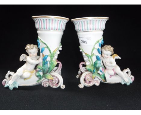 A PAIR OF CONTINENTAL CERAMIC STUDIES OF CHERUBS by cornucopia shaped vases